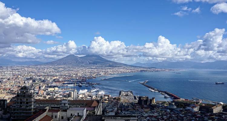 Vue panoramique d'une ville côtière avec le mont Vésuve en arrière-plan.