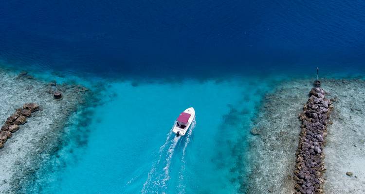 Bateau naviguant à travers des eaux turquoise avec des rochers de chaque côté.