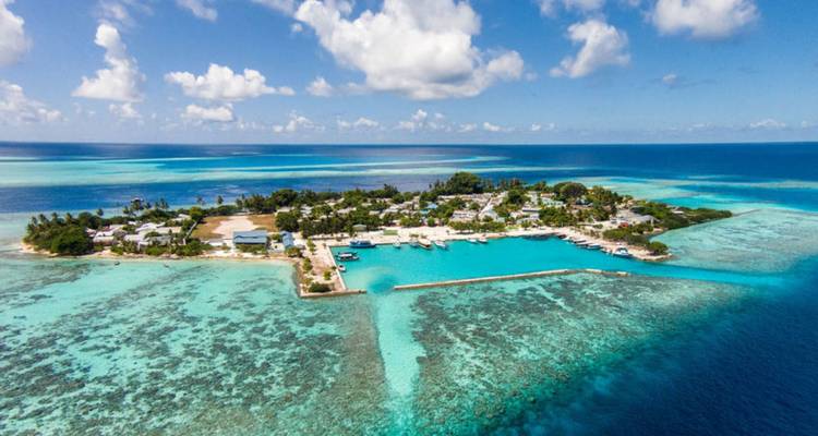 Vue aérienne d'un village insulaire entouré de récifs coralliens.
