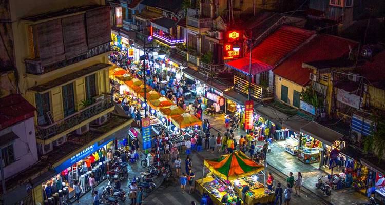 Un marché de nuit animé avec des étals colorés et des gens qui font leurs courses.