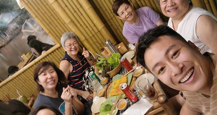 Un groupe de personnes souriantes à une table avec des plats vietnamiens traditionnels dans un cadre chaleureux.
