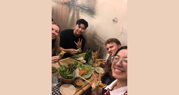 Groupe d'amis savourant un repas et posant pour un selfie à l'intérieur.