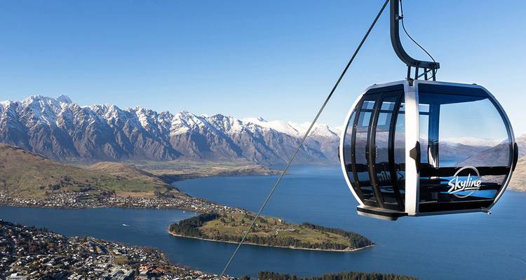 Une télécabine fermée s'élève au-dessus de Queenstown avec des vues panoramiques sur le lac Wakatipu et les sommets enneigés