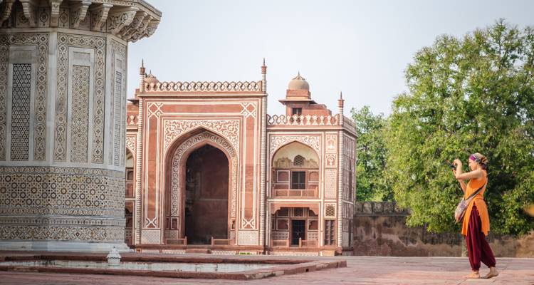 A photographer taking a picture near a historic tomb.