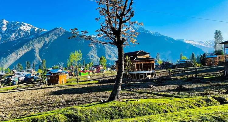 Scenic view of traditional houses with snow-capped mountains in the background.