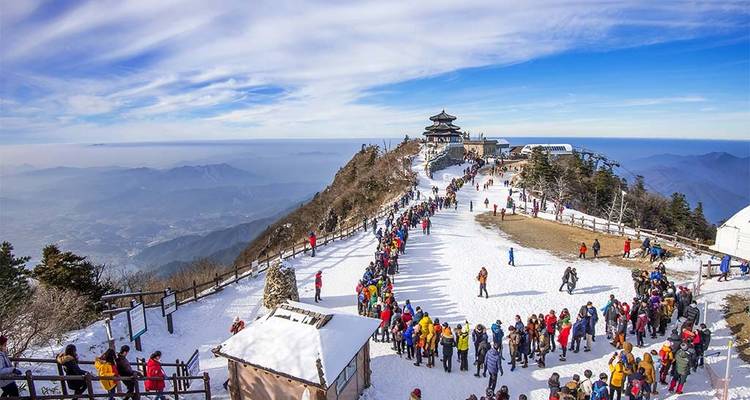 Busy ski resort at the top of a mountain with many visitors.
