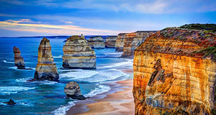 Dramatic coastline with tall rock formations and waves.
