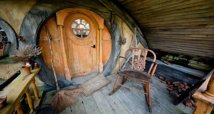 Porte ronde en bois fantaisiste et mobilier rustique d'un intérieur de maison de hobbit.