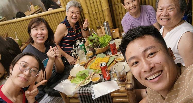 Groupe de personnes souriantes autour d'une table avec de la nourriture et des boissons vietnamiennes.