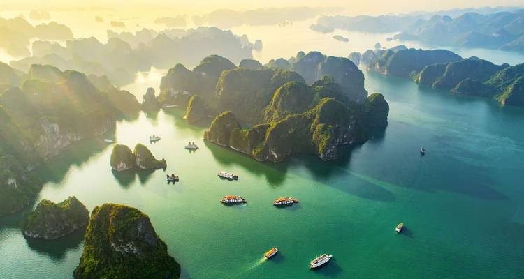 Îles calcaires dispersées à travers la baie d'Ha Long avec plusieurs bateaux.