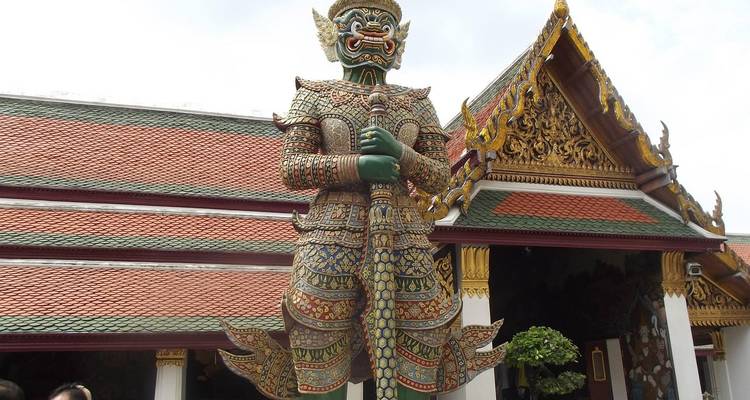 Statue gardienne géante devant un temple avec des détails complexes.
