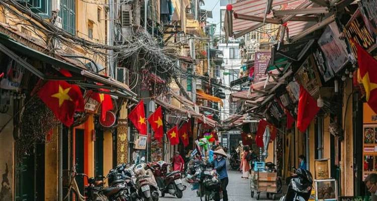 Bustling street with people and Vietnamese flags hanging overhead.