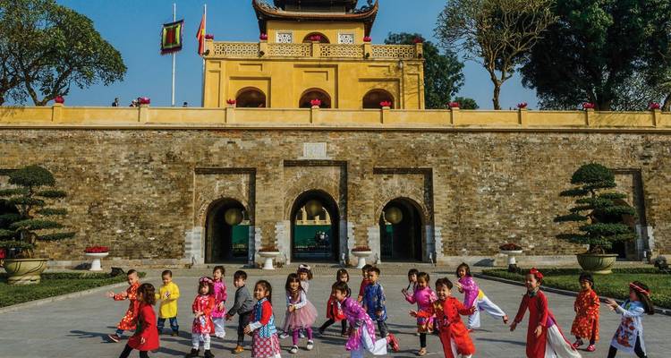 Children playing in front of a historic yellow building.