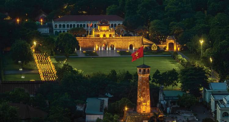 An aerial view of a lit courtyard at night with a Vietnamese flag.