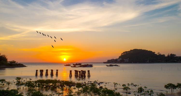 Coucher de soleil sur l'eau avec des oiseaux qui volent.