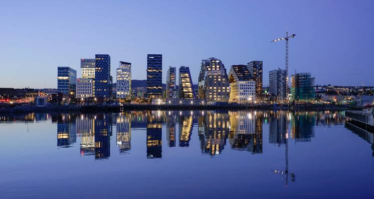 Silhouette de bâtiments modernes se reflétant sur l'eau au crépuscule.