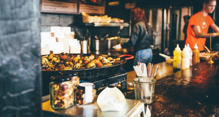 Scène de street food avec des vendeurs qui cuisinent et servent de la nourriture.