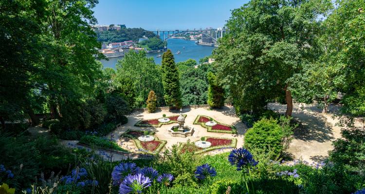 Garden with colorful flower beds overlooking a river and bridge.
