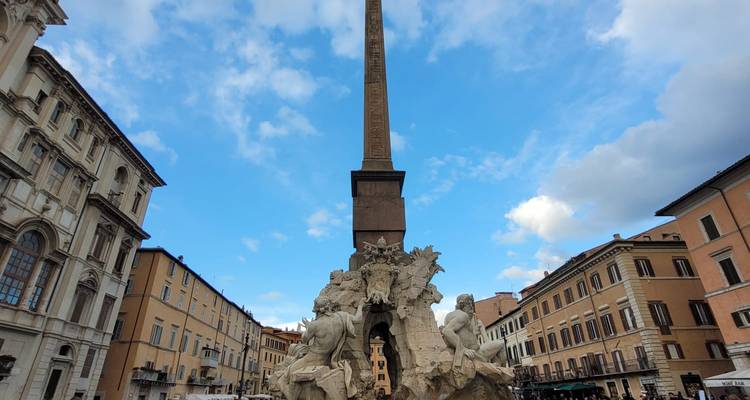 Brunnen mit Skulpturen und einem Obelisk auf einem Platz.