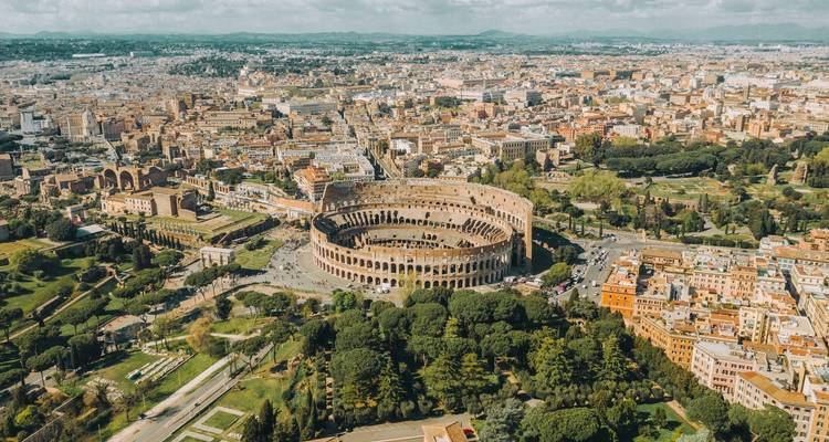 Aerial view of the Colosseum with Rome's cityscape in the background.