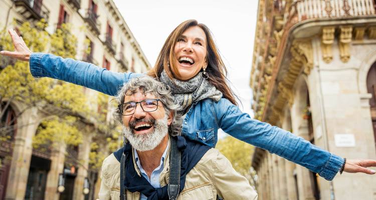 A happy couple in casual clothing posing in a city setting.