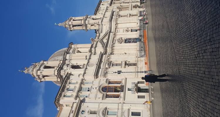 Baroque church facade with domes in a sunny piazza.