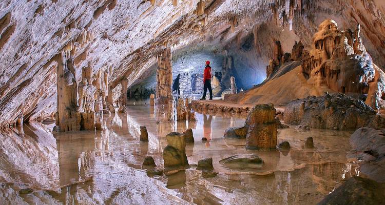 Explorateurs à l'intérieur d'une grotte magnifique avec des stalactites.