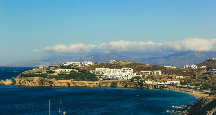 Luftaufnahme einer Küstenstadt mit Hügeln im Hintergrund.