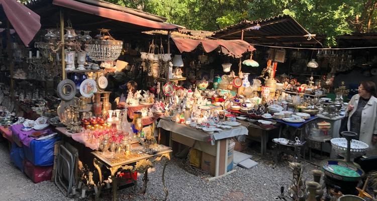 Étal de marché en plein air avec diverses antiquités et objets de collection.