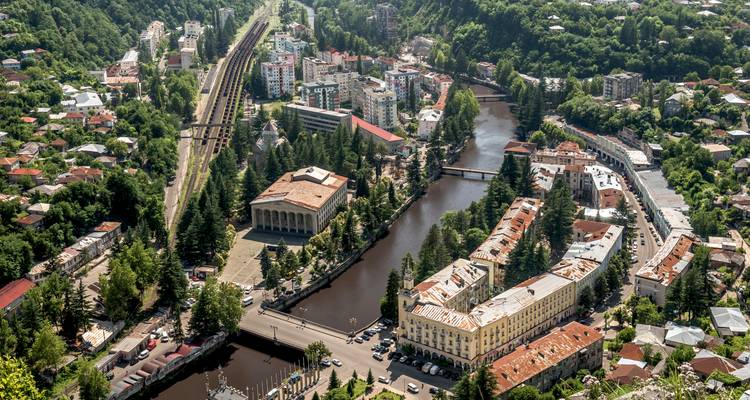 Luftaufnahme einer Stadt mit einem Fluss, der durch sie hindurchfließt und umgebender Vegetation.