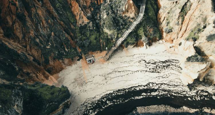 Staircase leading down to a secluded beach between cliffs.