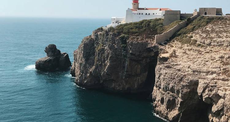 Coastal view of a lighthouse perched on cliffs above the sea.