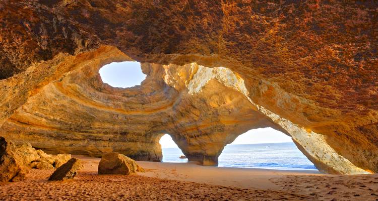 Famous Benagil cave with holes in the ceiling and beach.
