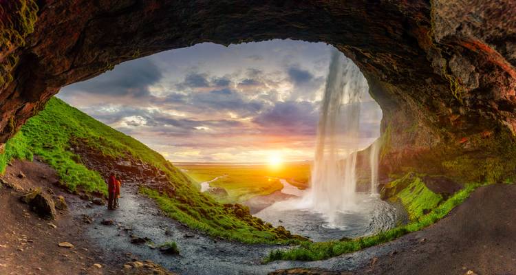 Vue spectaculaire d'une cascade depuis une grotte avec la lumière du soleil qui traverse.