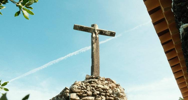 Stenen kruis tegen een blauwe lucht.