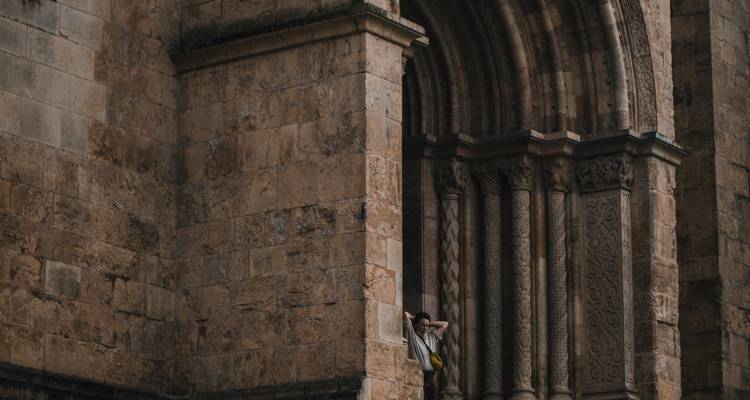 Persoon leunend tegen een oud stenen gebouw.