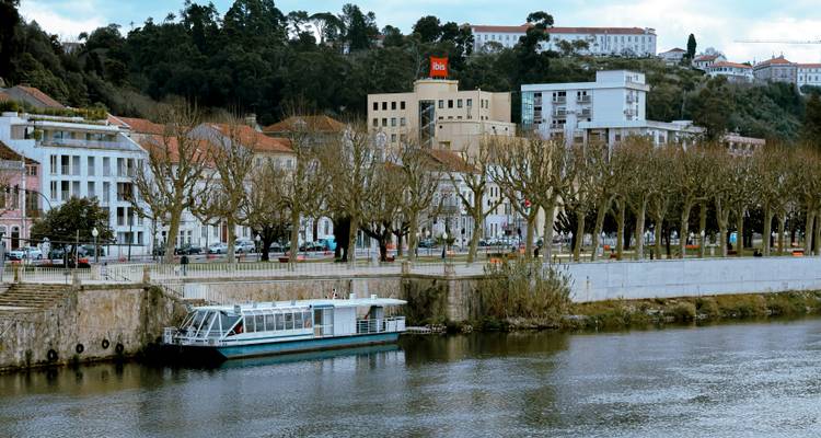 Rivier met aangemeerde boot en stadsgebouwen op de achtergrond.
