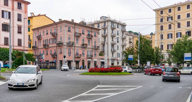 Stadsgezicht met rotonde en kleurrijke gebouwen, met auto's in beweging.