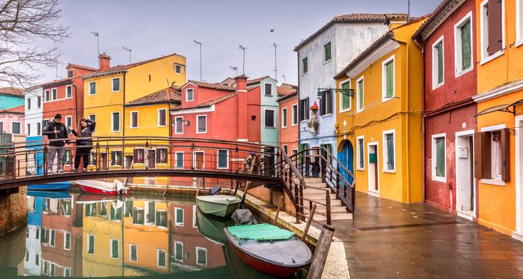 Kleurrijke huizen langs een kanaal in Burano met een kleine brug en boten.