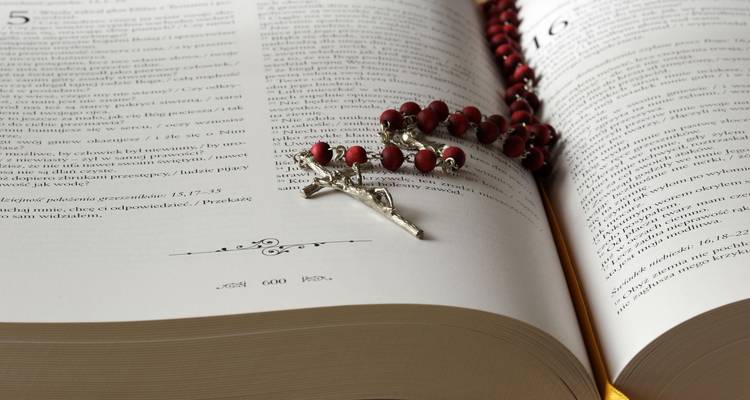 Un libro religioso abierto con un rosario encima.