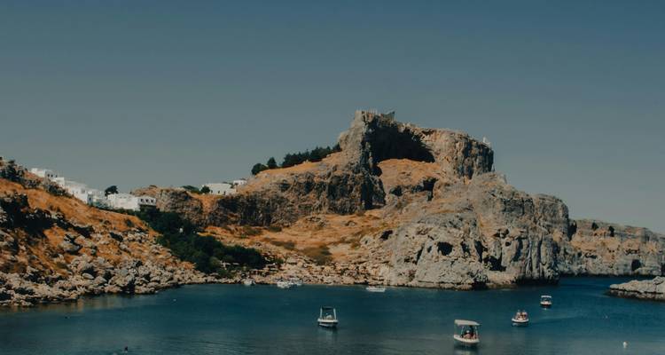 Vista costera con barcos cerca de acantilados rocosos.