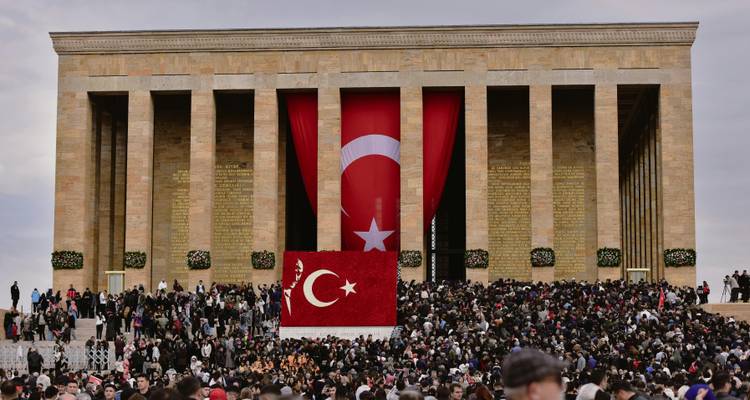 Crowd in front of a building with a Turkish flag.