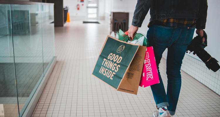 Person carrying shopping bags in a shopping mall.