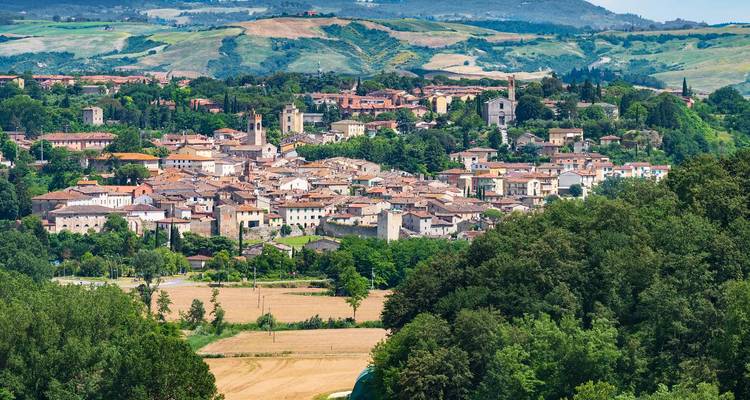 Panoramic view of a small Tuscan town surrounded by lush hills.