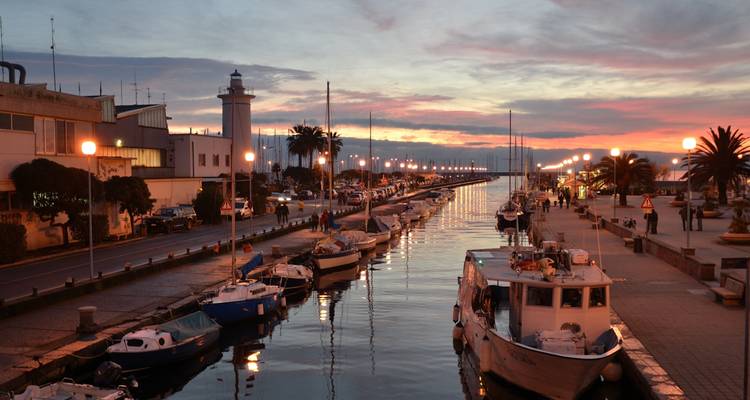 A canal lined with boats at sunset.