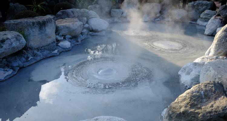 Geothermal hot spring with steam and rocks.