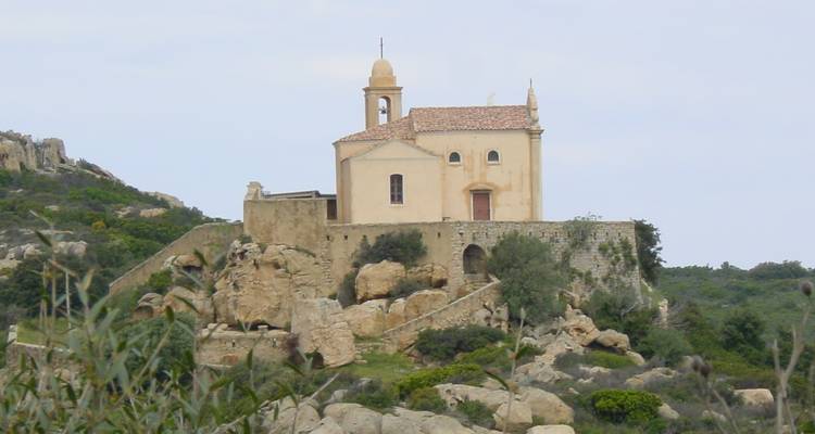 Pequeña capilla en la cima rocosa de una colina bajo un cielo nublado