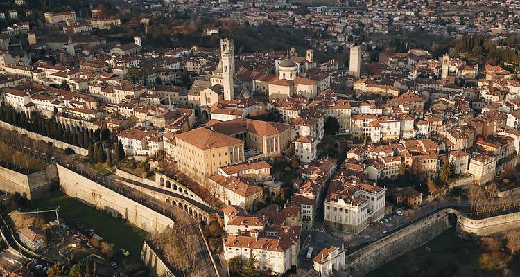 Vista aérea de una ciudad histórica con murallas y edificios de tejados rojos.