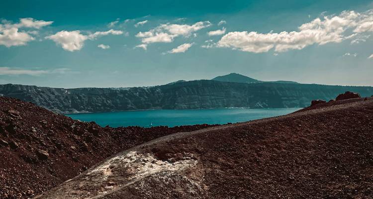 Paysage volcanique accidenté avec une vue lointaine sur la mer.