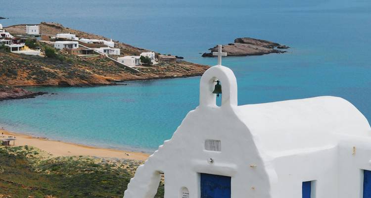 Une vue panoramique d'une chapelle blanche avec un clocher au bord de la mer avec une côte rocheuse et une eau turquoise.
